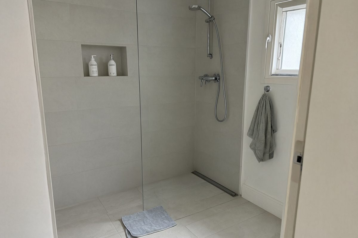 Douche de plain-pied avec paroi vitrée fixe, niche murale et caniveau de sol