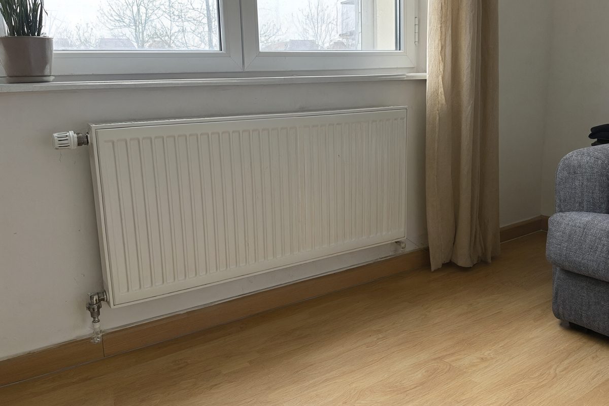 Radiateur à panneaux blanc avec vanne thermostatique sous une fenêtre de salon