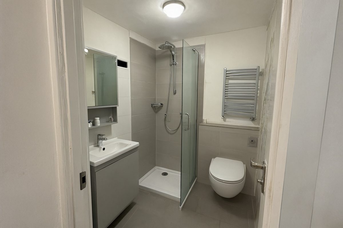 Petite salle de bain avec douche d'angle, WC suspendu et meuble vasque étroit