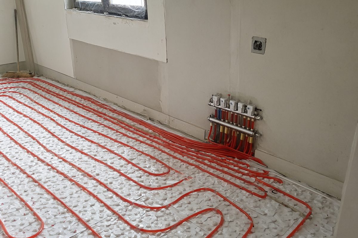 Tubes de chauffage par le sol posés sur des panneaux isolants, raccordés à un collecteur